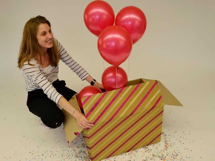 Vrouw doet doos open met ballonnen in