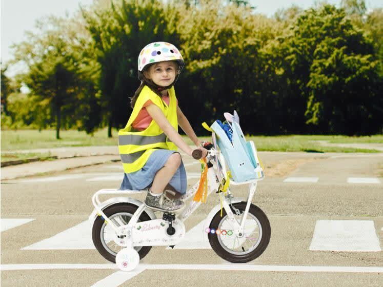 Meisje met fluohesje op kleurrijke fiets