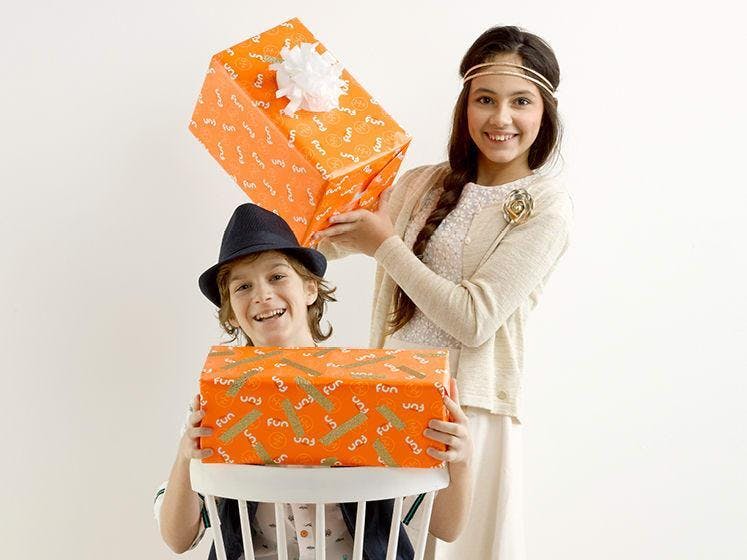 Jongen en meisje mooi gekleed met elk een oranje pakje in de handen