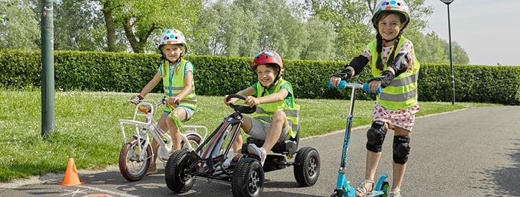 3 kinderen op een fiets, gocart, step aan de startlijn